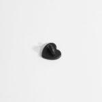 A photo of a black, heart-shaped rubber pin backing.