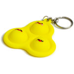 Low angle photo of a yellow silicone Chicky Pop-It fidget toy. Features three adorable chicky faces!